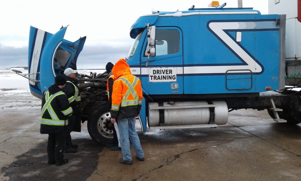 People standing in front of a truck with an open hood.